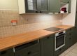 Agencement cuisine à Tours avec meubles vert olive, plan de travail bois et papier peint panoramique