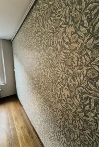 Rénovation d’une chambre à Tours avec murs et plafond repeints et pose d’un papier peint floral dans les tons vert et beige.